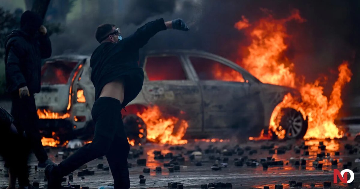 Tirana, 17/10/2026: un manifestante con il volto coperto lancia un oggetto davanti a un'auto in fiamme, quinto giorno delle proteste. Foto: SyriTv, Wikimedia Commons, CC BY-SA 4.0, 17/10/2026, ritagliata